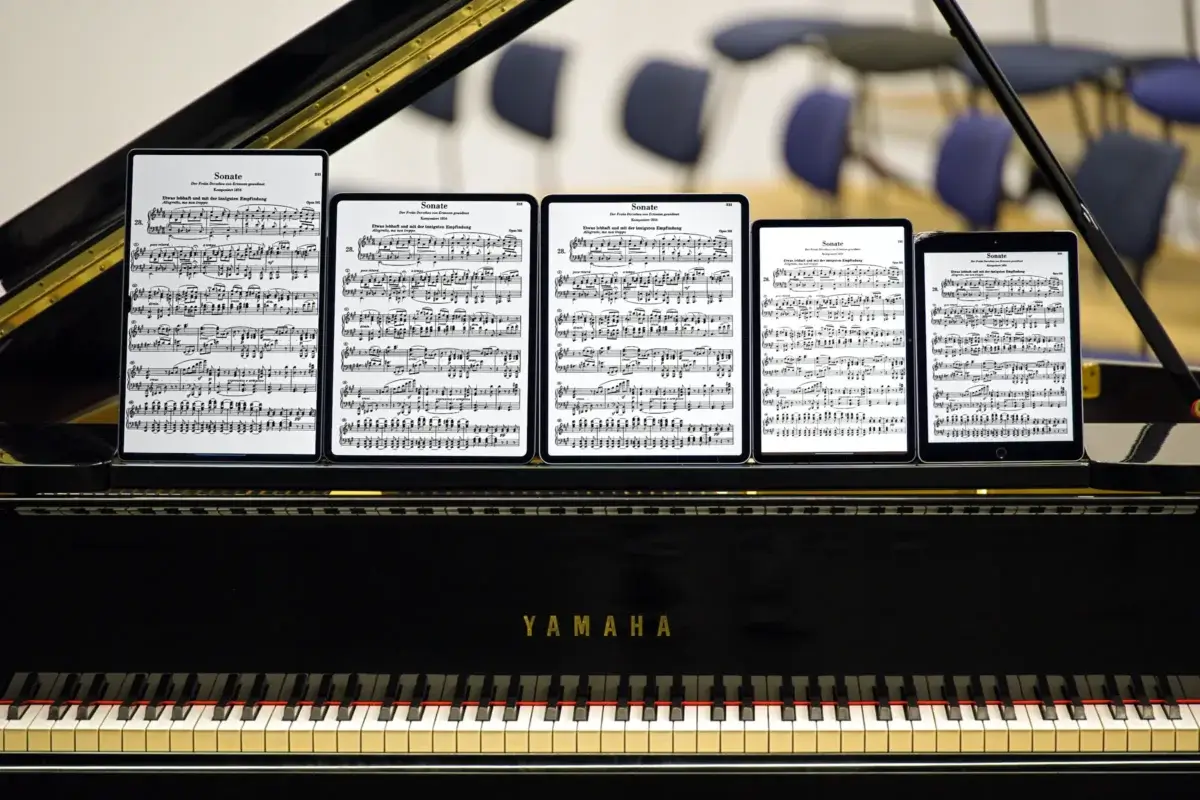 Notenblätter auf fünf iPads und Tablets auf einem Klavier